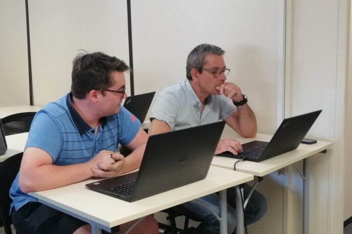 Directeur de Green IT Solutions et son apprenti assis à une table en train de vérifier sur leurs ordinateurs les réseaux de notre client à Poitiers;